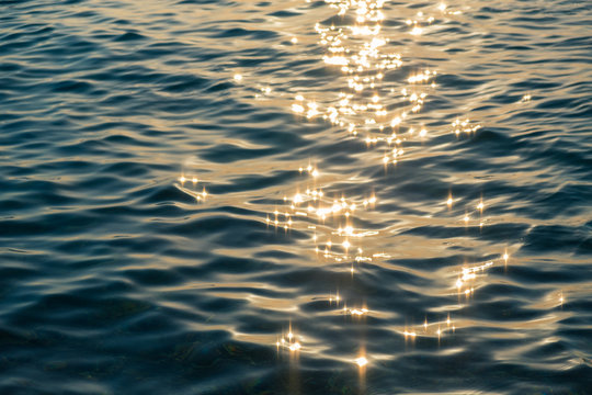Ripples on the water surface with sun rays glittering 