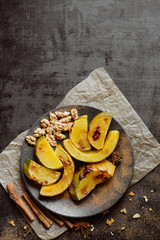 Baked pumpkin with spices in a plate on a dark background
