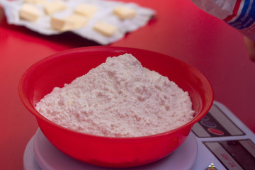 flour in a red bowl stands on the scales.