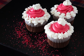 Christmas chocolate cupcakes pink cream cheese frosting. Dark background. Selective focus.