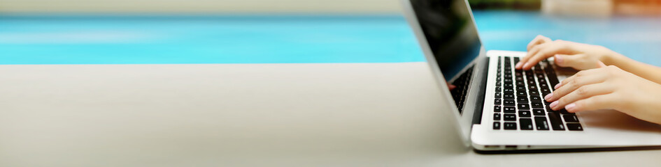 Banner with copyspace in grey color of laptop and female hands, blue background. Concept of website...