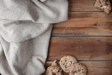 Old wooden background and knitted warm pullover. Autumn decor and biscuit liver with chocolate. Free space for text. Top view