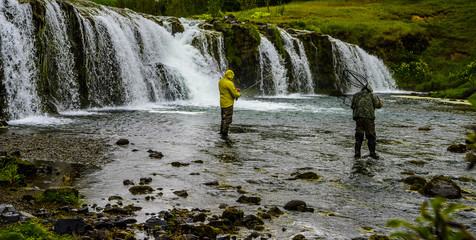 Fishermen fly fishing at fast flowing waterfall