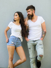 Urban loving couple. Couple stylish young modern people. Couple white shirts lean each other. Hipster bearded and stylish girl hang out outdoors. Couple in love hang out together grey wall background