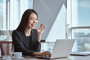 Businessperson at office alone sitting having video call smiling