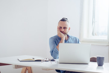 Young businessman working on laptop / Young man working on his desk.