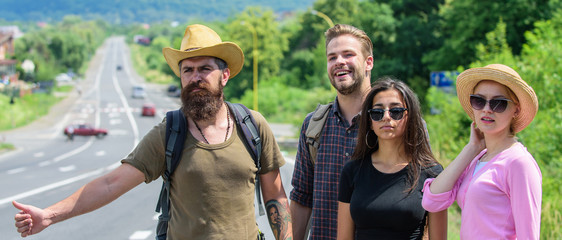 Travellers try to stop car. Friends hitchhikers travelling summer sunny day. Begin great adventure in your life with hitchhiking. Company friends travelers hitchhiking at edge road nature background