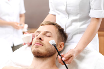 Maseczka oczyszczająca, męska pielęgnacja.
Mężczyzna w salonie kosmetycznym na zabiegu pielęgnacyjnym skóry twarzy.
