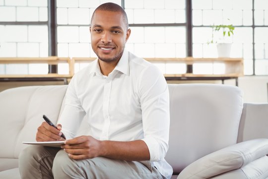 Smiling therapist writing on book at clinic 