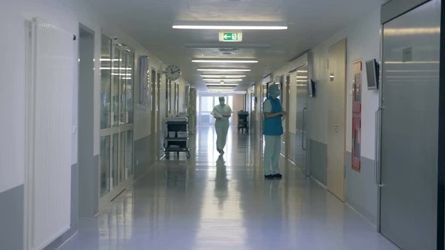 Hospital corridor with one doctor standing and one doctor walking along it