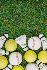 Naklejka premium top view of arrangement of badminton shuttlecocks, tennis and baseball balls on green lawn