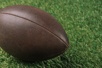close up view of leather rugby ball lying on green grass