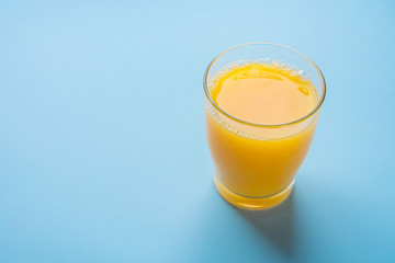 Glass of Freshly Pressed Orange Citrus Juice on Light Blue Background. Freshness Healthy Drink Detox Breakfast Morning. Funky Hipster Modern Style. Poster with copy space
