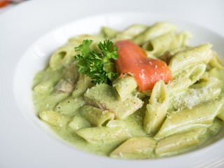 Traditional Italian Penne pasta with pesto sauce and salmon.