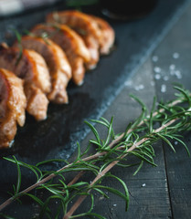 Close-up of fresh rosemary with roasted pork chops in background
