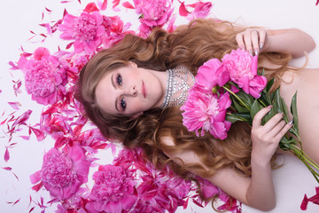a girl lying in red peonies