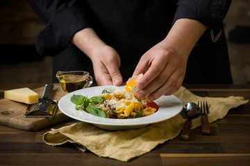 Chef serving Italian pasta with cheese, vegetables and egg yolk. Dark background copy text.