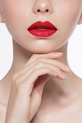 Obraz na płótnie Canvas Close-up of female plump red lips and clean skin. The model touches the hand demonstrating skin care. Beauty and spa procedures, injections and lip augmentation