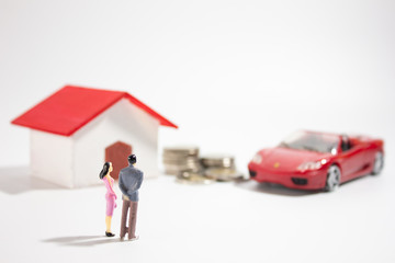 Miniature family with miniature house and car medium closeup.