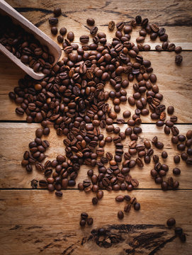 Coffee beans and scoop on wooden background, top view