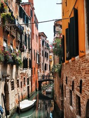 The canal is surrounded by ancient buildings, gondolas and boats in Venice