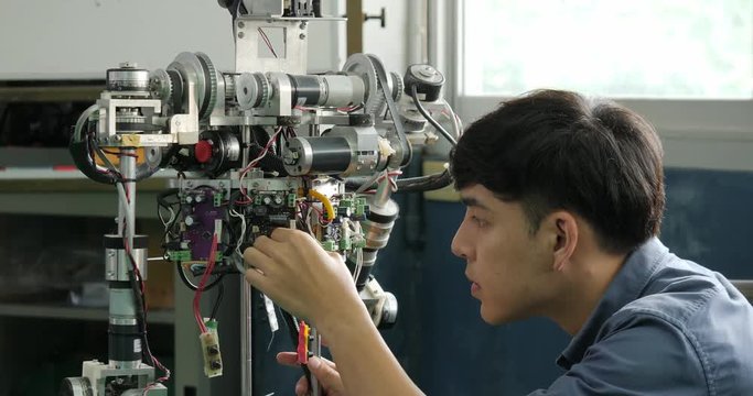 Asian young electronics engineer building, fixing robotics in laboratory. People with technology or innovation concept.