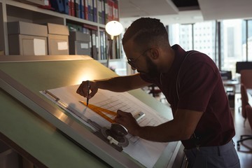 Architect working on blueprint on drafting table