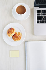 Danish pastry, coffee and laptop on desk of office manager