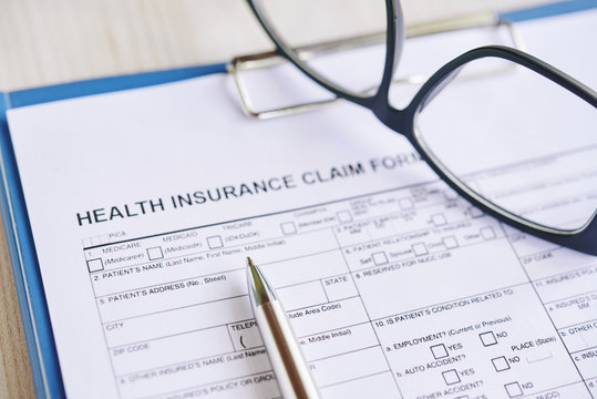 Health insurance claim form with glasses and pen