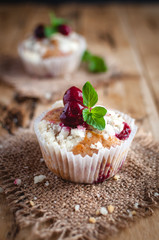 Close-up of cherry muffin with crumbly topping on wooden background 