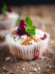 Close-up of cherry muffin with crumbly topping on wooden background 