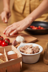 cropped shot of woman cooking pasta with bowl of chicken meat on foreground