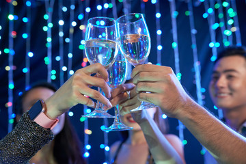 Hands of people toasting with glasses of wine in night club at party