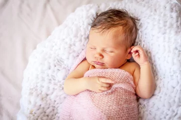 Fototapeten Cute Caucasian newborn infant baby girl asleep wrapped in a soft pink plaid.  Adorable newborn baby girl portrait studio stock image. © Roman Yanushevsky