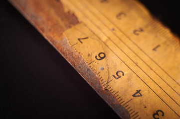 Old rusty metal ruler on black background surface