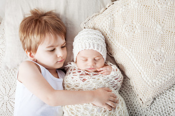 Portrait of newborn baby and elder brother. Young boy lying with newborn brother. © fadzeyeva