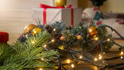Closeup image of glowing Christmas garland and gifts in boxes on wooden background