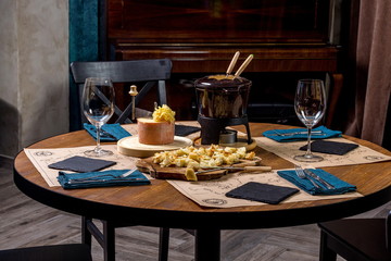 Gourmet fondue with a variety of cheeses on the board along with a warmed pot of cheese fondue.