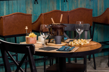 Gourmet fondue with a variety of cheeses on the board along with a warmed pot of cheese fondue.