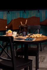 Gourmet fondue with a variety of cheeses on the board along with a warmed pot of cheese fondue.