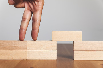 Businessman hand walking across risk between wood blocks