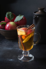 Glass of tea with lemon, spiced, sliced apple and cinnamon on black board. Autumn still life.