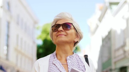 travel, tourism and retirement concept - senior woman or tourist walking with city guide
