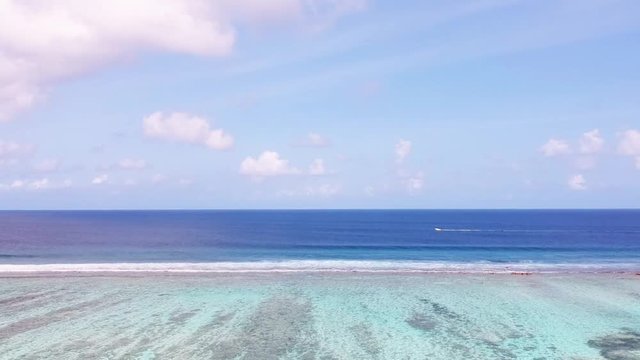 Aerial over ocean with breakwaters and a speedboat