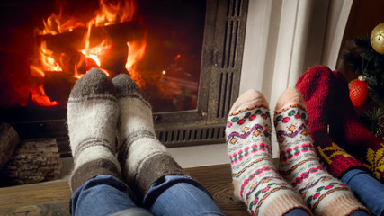 Closeup photo of three persons in woolen socks warming at the fireplace