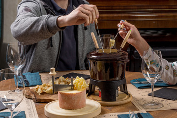 Gourmet fondue with a variety of cheeses on the board along with a warmed pot of cheese fondue.