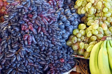 Natural vegetative texture of ripe berries of grapes and bananas of blue and yellow color