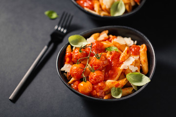 Tasty tomato pasta in bowl on dark