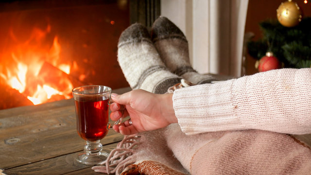Closeup image of woman drinking mulled wine in living room y the fireplace