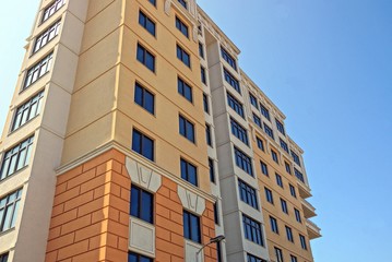part of a large tall brown house with windows on the sky background
